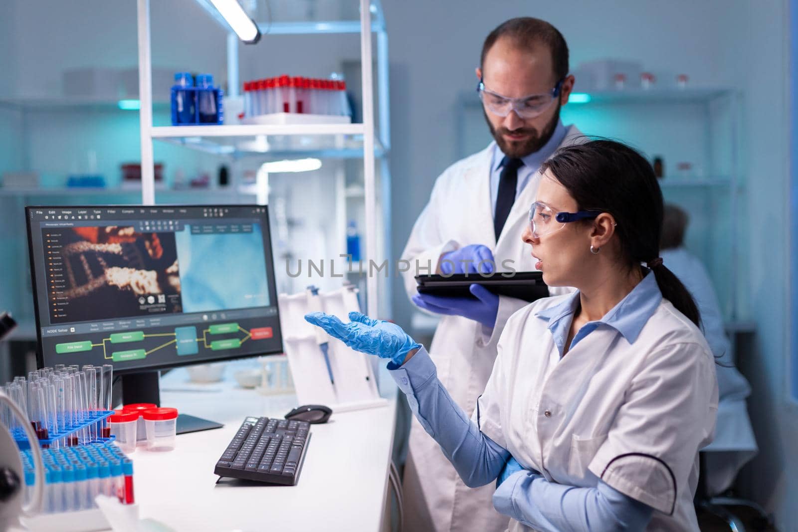 Biotechnology scientists teamworking at computer researching in development laboratory. Doctors specialists discovering scientific experiment in modern lab developing and stying new type of vaccine