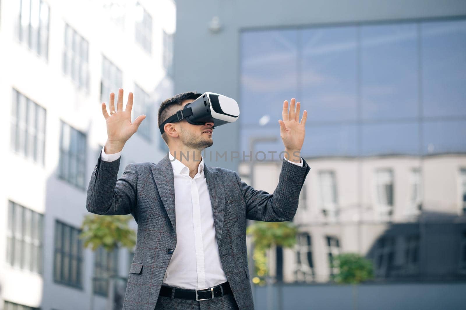 Handsome man wearing virtual reality headset. Augmented Reality. Businessman touch something using modern 3D vr glasses near office building. This new technology offers new 3D dimensions.