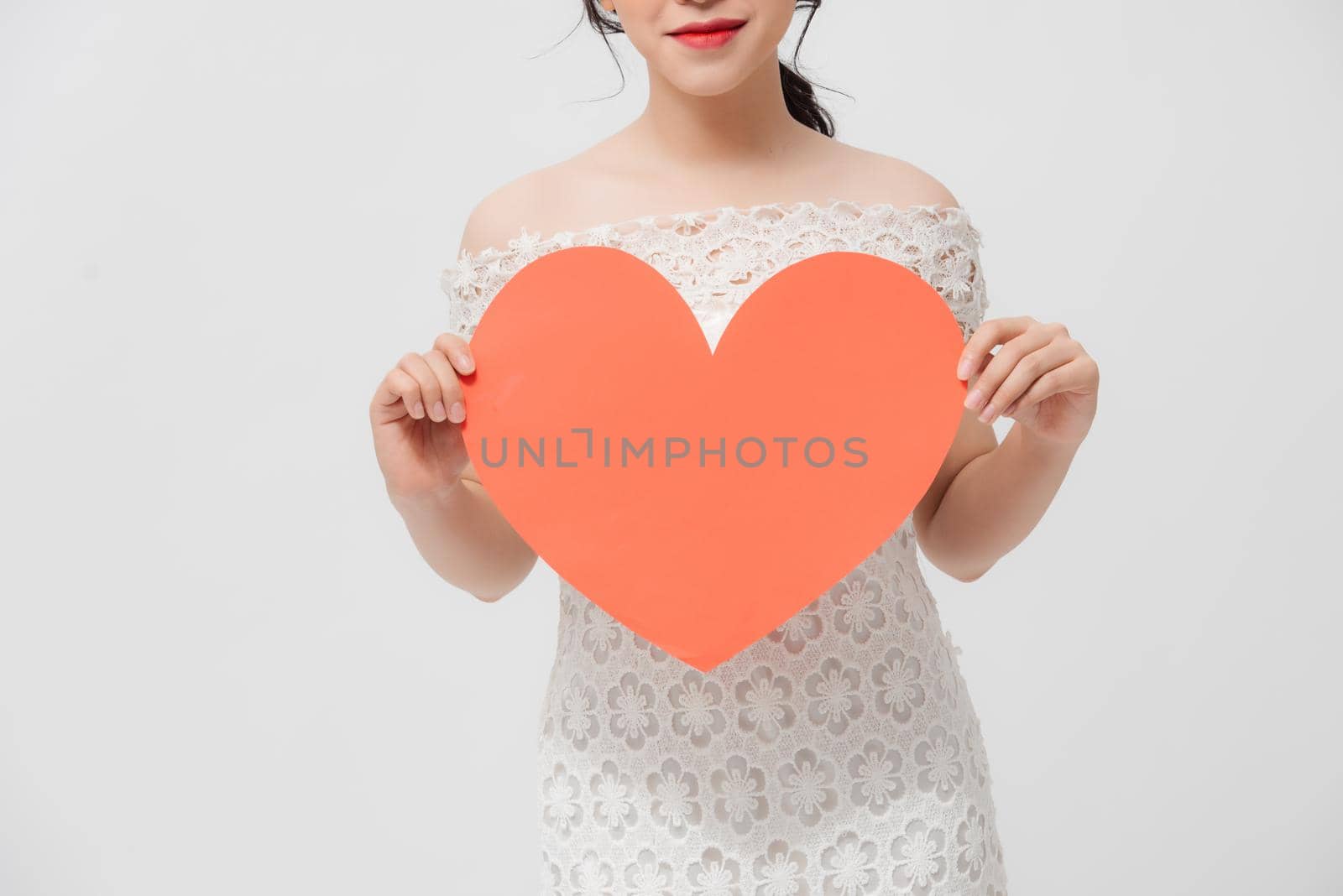 Attractive young Asian woman holding red love shape and standing over white background. by makidotvn