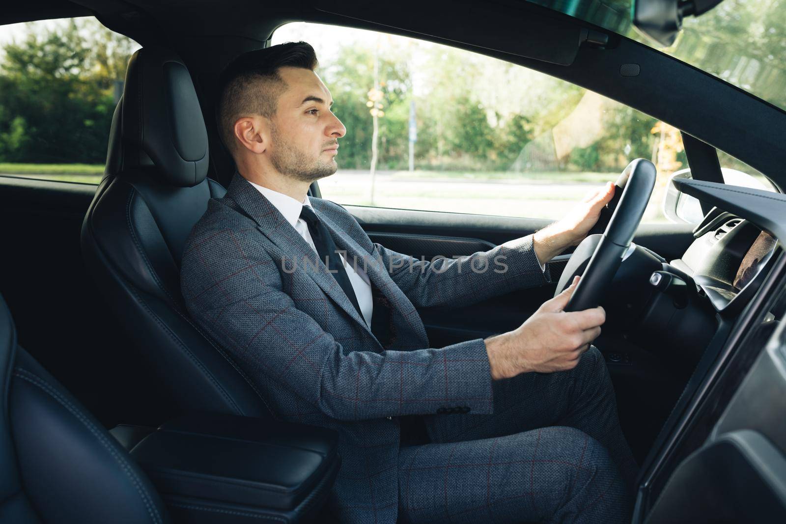 Portrait of successful start-up developer engineer boss executive on drive. Handsome young businessman in car. People and transportation.