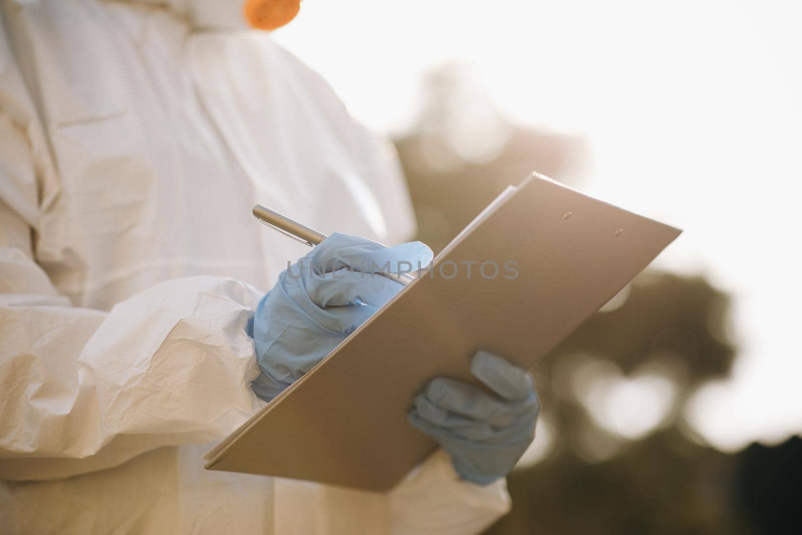 The Virologist hand in a white glove holds a pen on a blank sheet of paper. The doctor holding clipboard with blank paper in the hand.