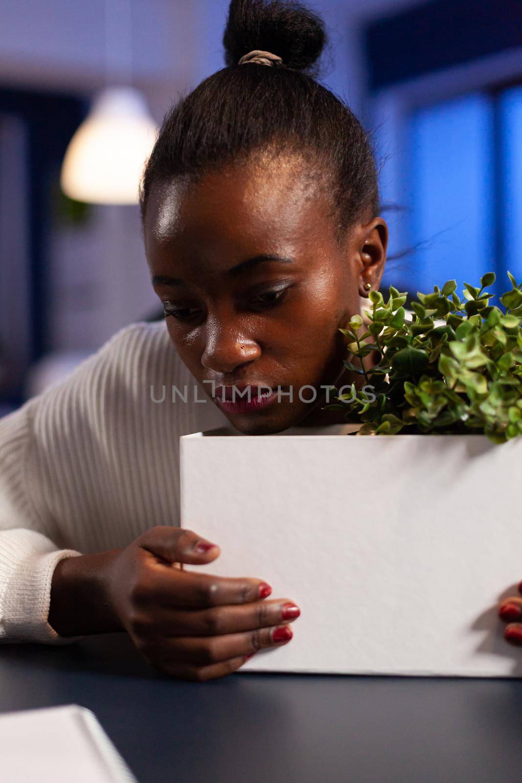 Close upf sad depressed african woman after bing dismissed from work during economy crisis. Unemployed packing things late at night. woman leaving workplace office in midnight.