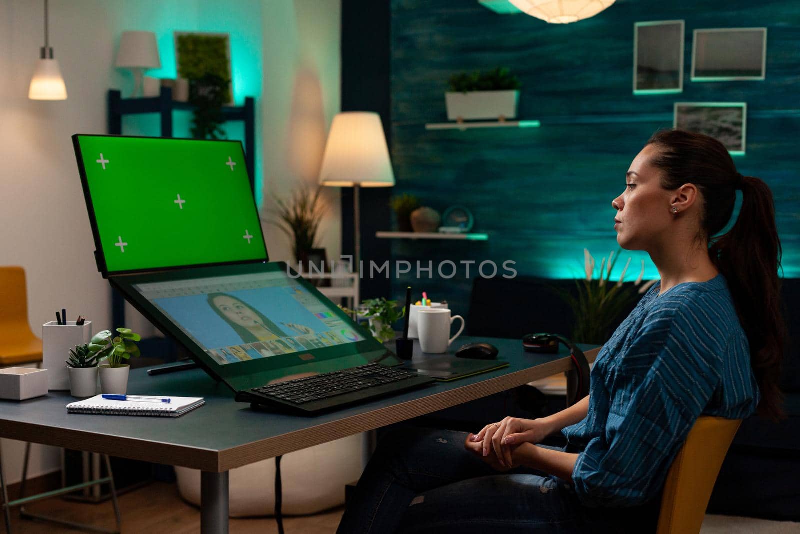 Professional photographer working with green screen and editing photo on touch display computer. Artist woman retouching project, digital chroma key, mockup template on desktop office
