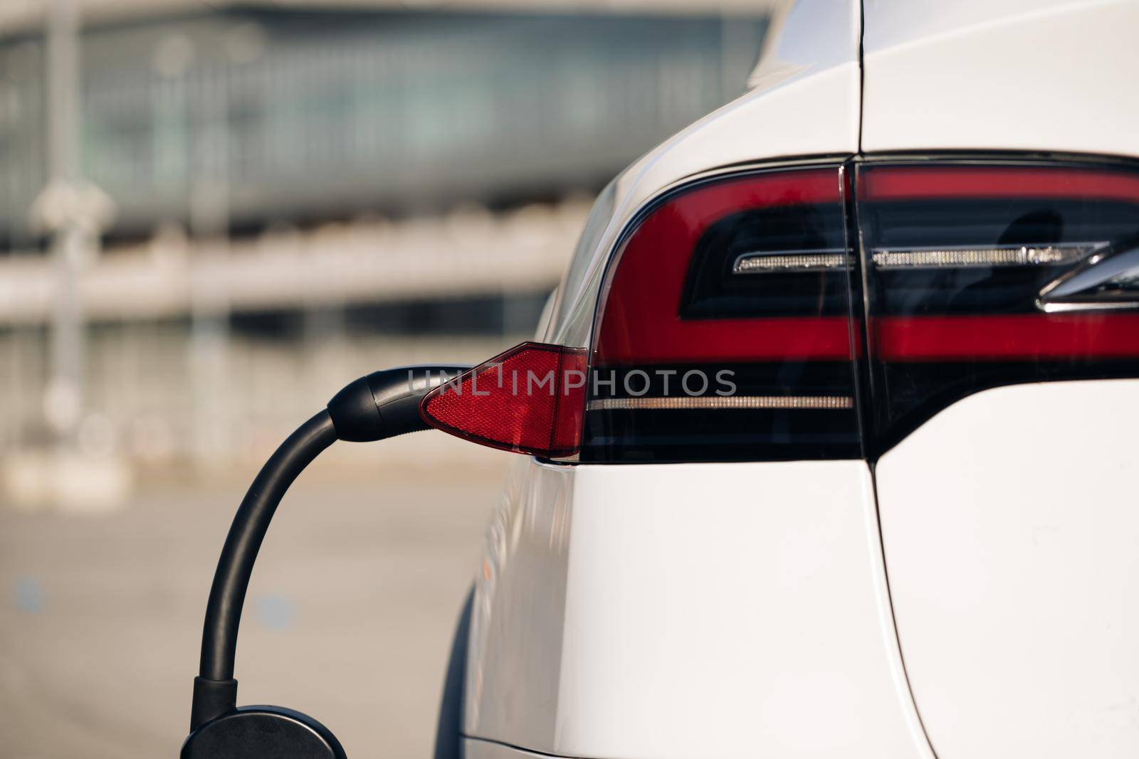 Plug charging an electrical car. Electric vehicle charging port plugging in EV modern car. Save ecology alternative energy sustainable of future.