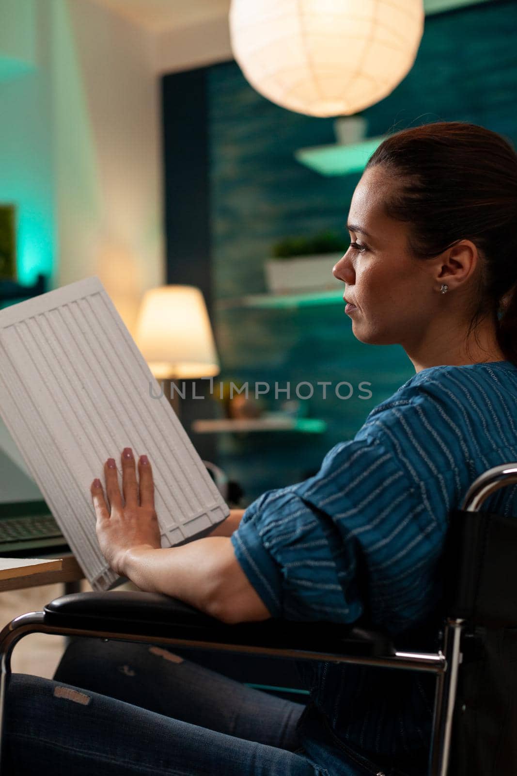 Disabled engineer sitting in wheelchair with maquette building icon model for blueprint sketch plan. Business woman working on construction design for futuristic property renovation