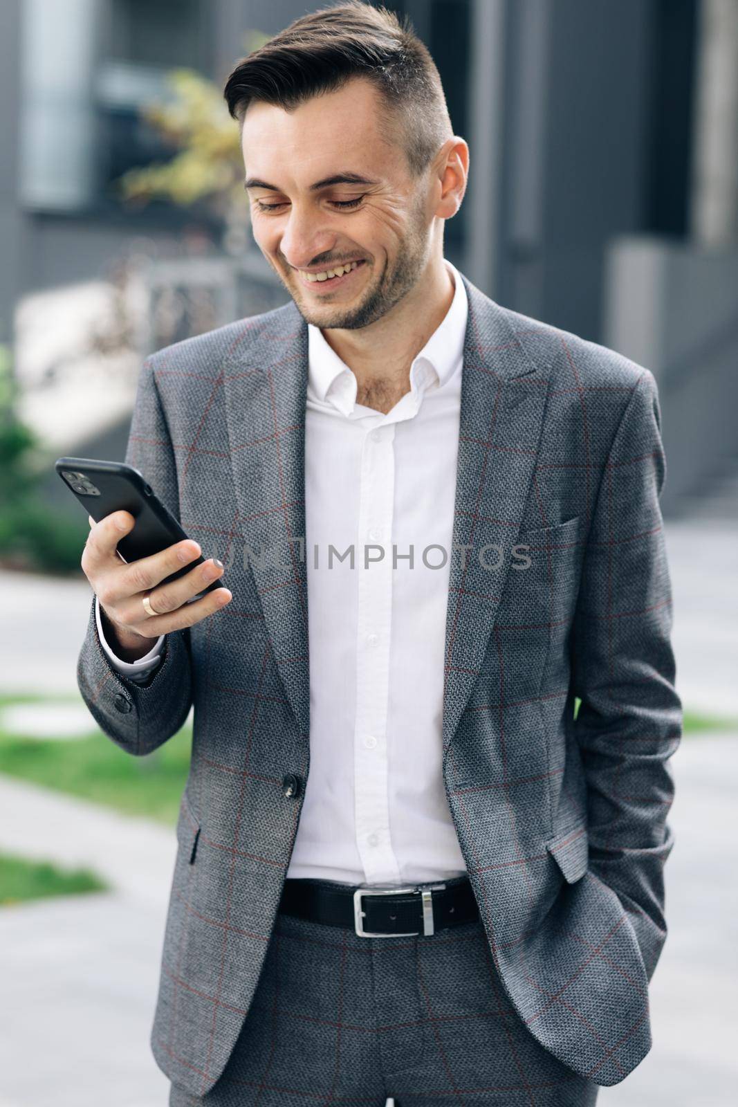 Footage from Outside: Handsome bearded businessman using mobile phone. Young man texting messages, cheating on his smartphone near business center. Vertical Screen Orientation. by uflypro