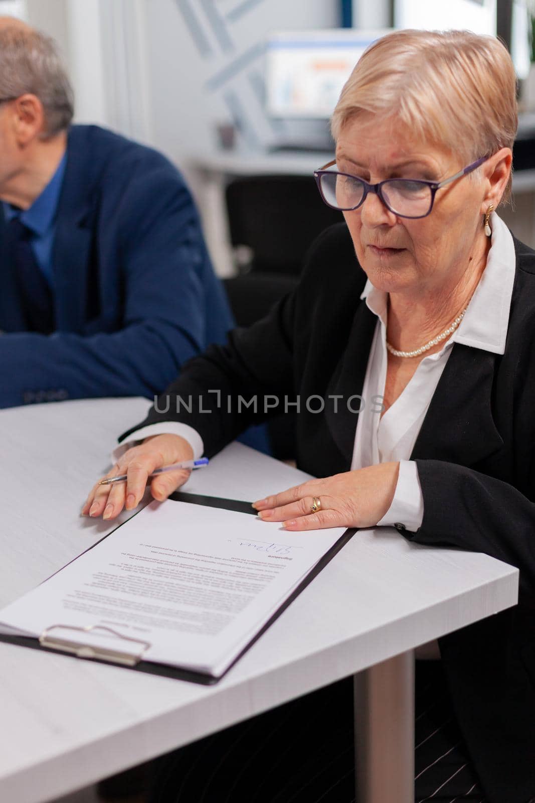 Woman reading financial documents in conference room before signing it. Executive director meeting shareholders in start up office, making satisfactorily agreement.