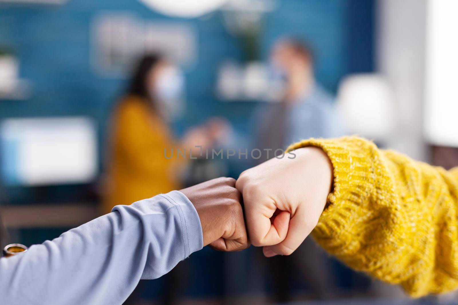 Close up of african woman and friend doing fist bump greeting each other in hme living room keeping social distancing as safety precaution during global pandemic with coronavirus.