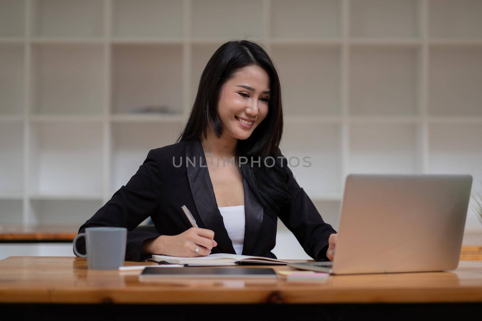 Asian business woman working on laptop computer during taking notes at the office