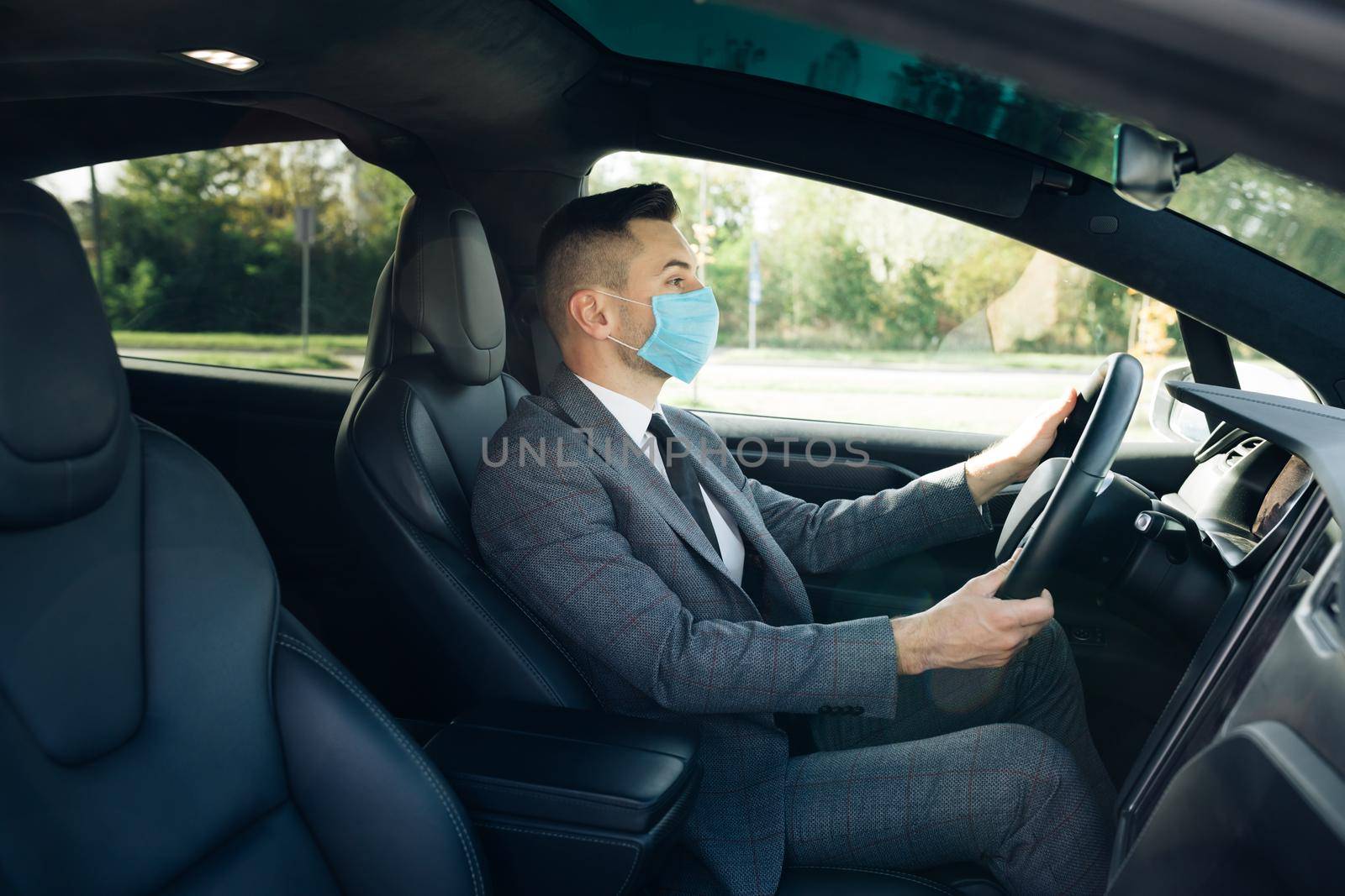 Pandemic. Citizens. Lockdown safety. Adult businessman wearing medical mask in prevention for coronavirus and driving his car to work. Businessman healthcare.