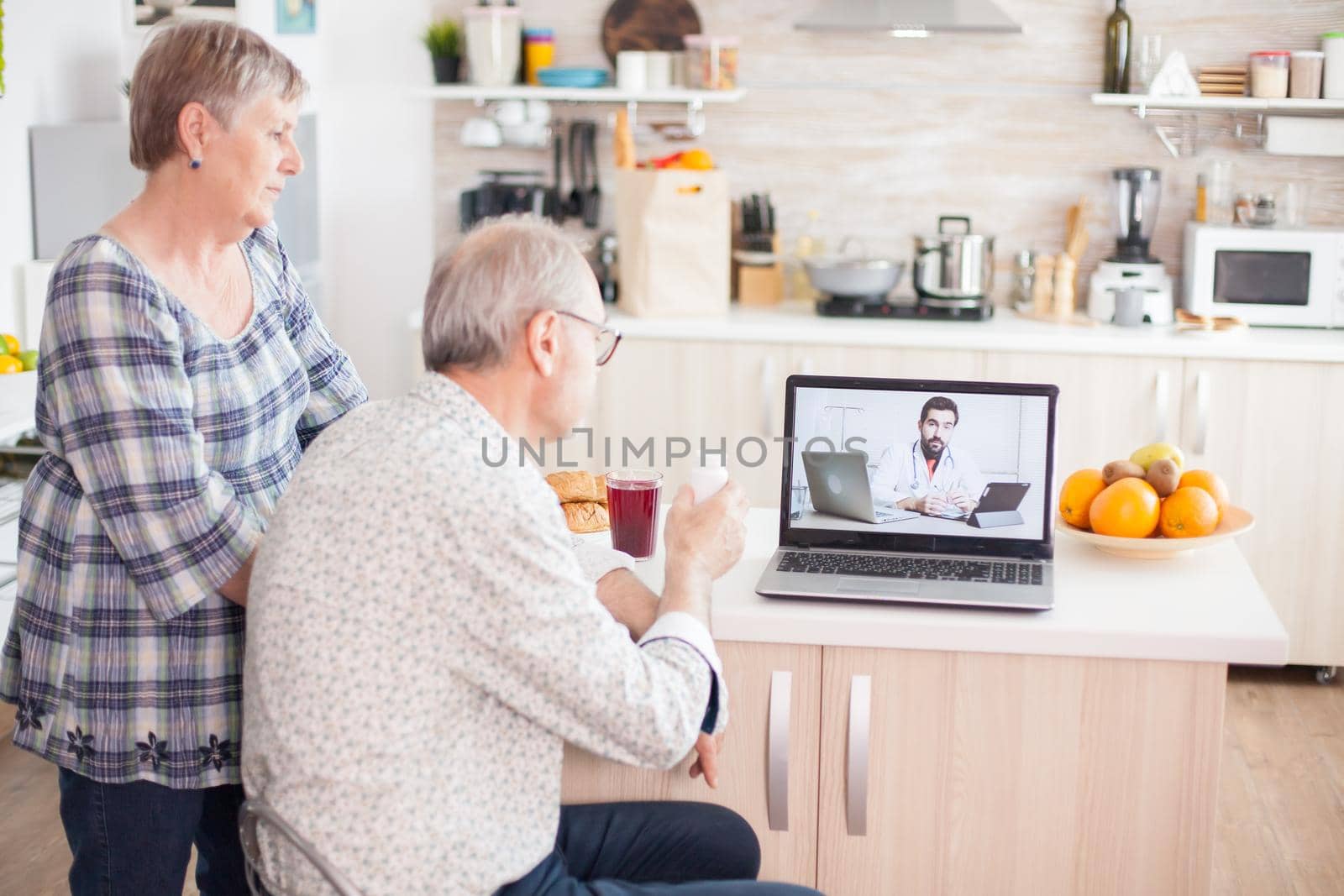 Video conference with doctor using laptop in kitchen. Online health consultation for elderly people drugs ilness advice on symptoms, physician telemedicine webcam. Medical care internet chat