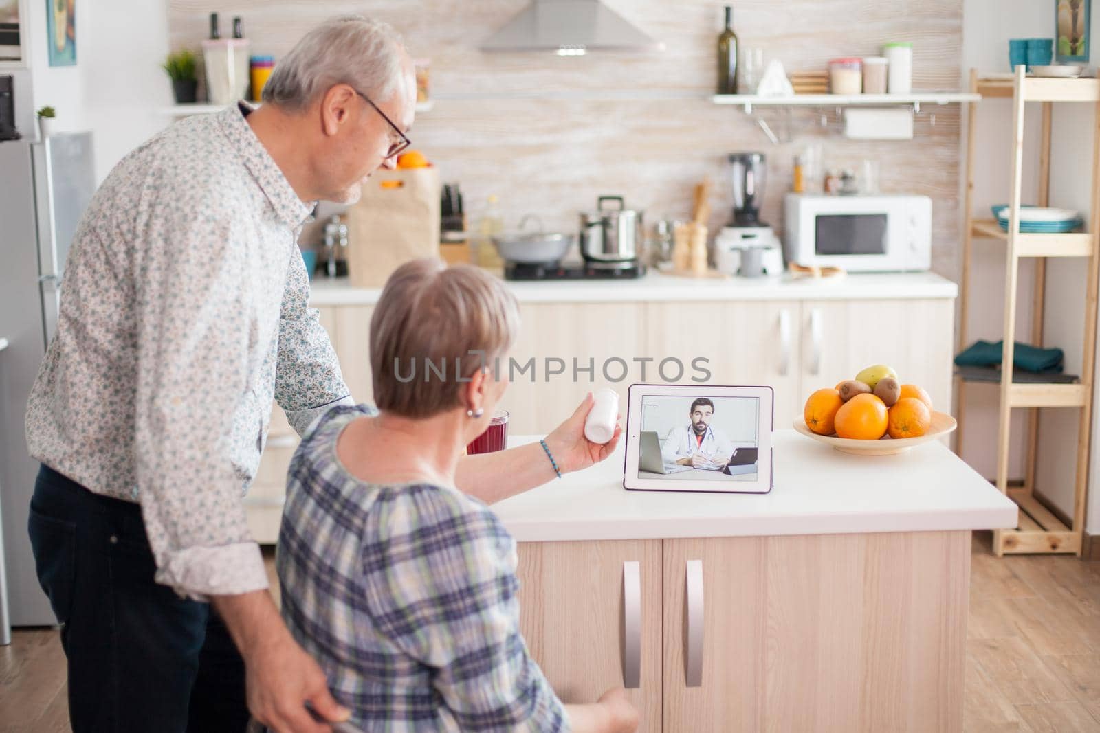 Old couple during online consultation with doctor. Video conference with doctor using laptop in kitchen. Online health consultation for elderly people drugs ilness advice on symptoms, physician telemedicine webcam. Medical care internet chat