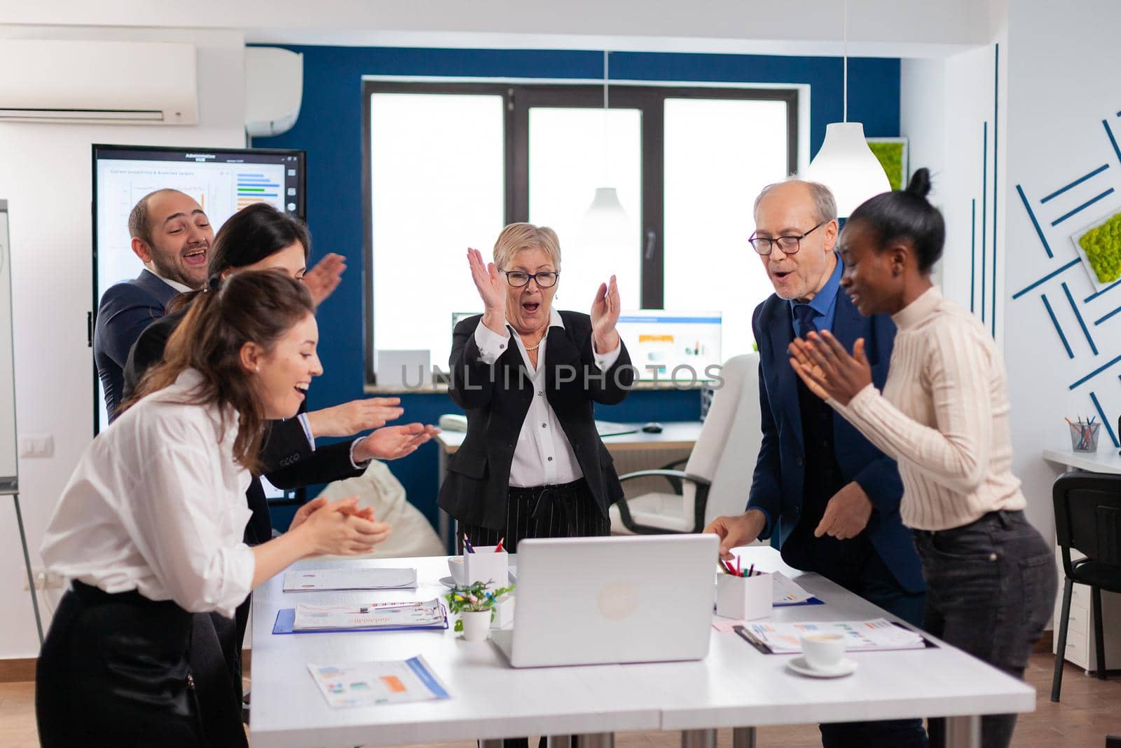 Diverse executive business team clapping in conference room during training. Multiethnical partners coworkers celebrate successful teamwork result at company briefing