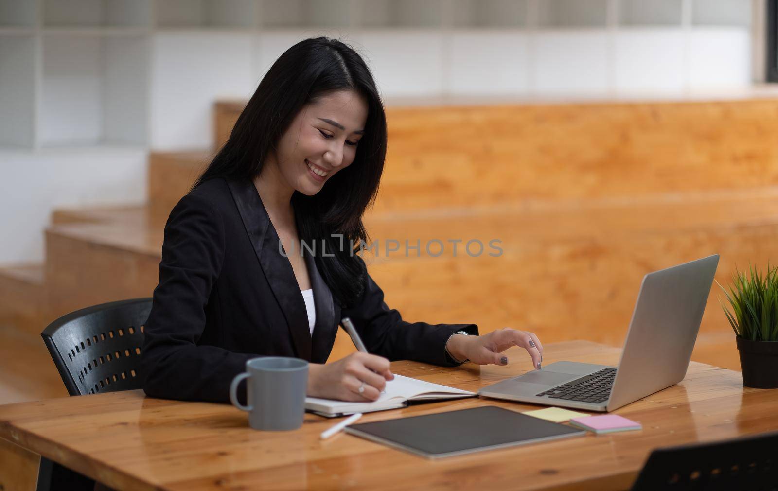 Asian business woman working on laptop computer during taking notes at the office. online meeting webinar concept. by nateemee