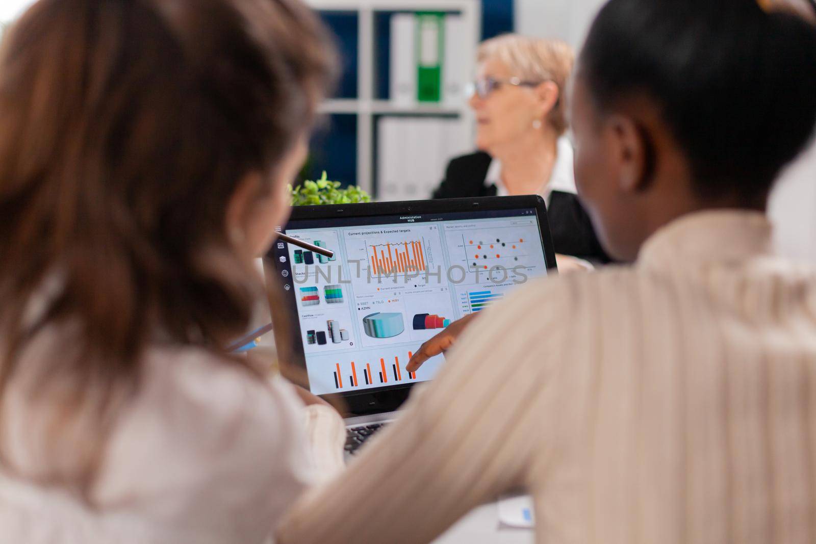 African american entrepreneur and coworkers analysing charts in conference room. Businesswoman discussing ideas with colleagues about financial strategy for new start up company working in brainstorming office.