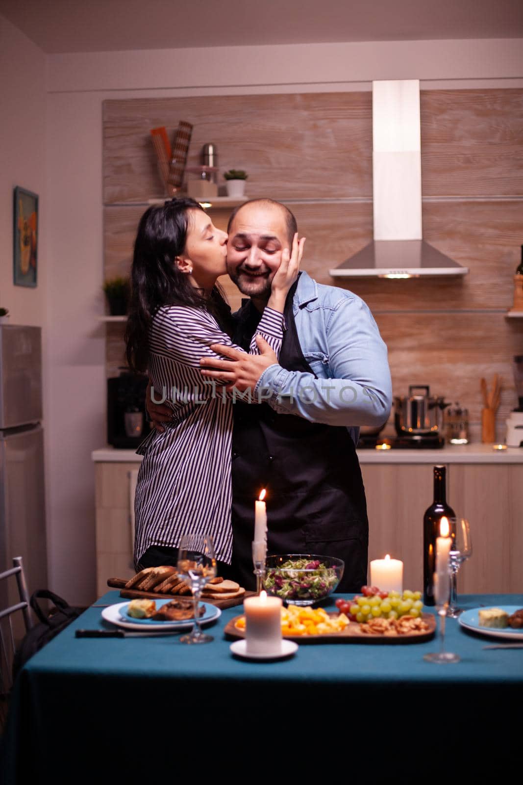 Wife giving husband affection in kitchen during romantic date in the evening. Man preparing festive dinner with healthy food, cooking for his woman a romantic dinner,