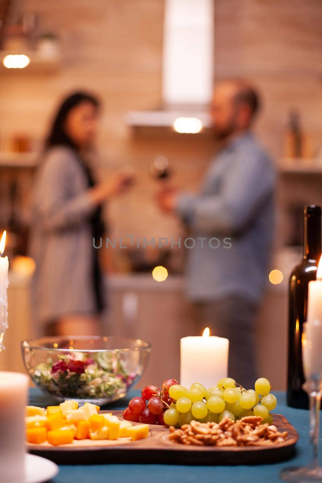 Close up of grapes on wooden board while couple having romantic dinner.