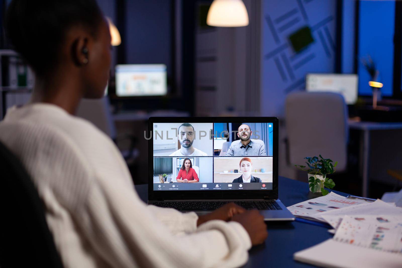 African businesswoman talking during video conference with team in midnight using laptop in start up business office. Diverse workers talking during corporate meeting using technology network wireless.