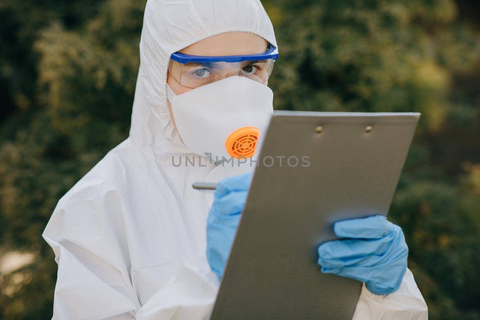 Doctor epidemiologist fighting with coronavirus COVID-19. The Virologist hand in a white glove holds a pen on a blank sheet of paper by uflypro