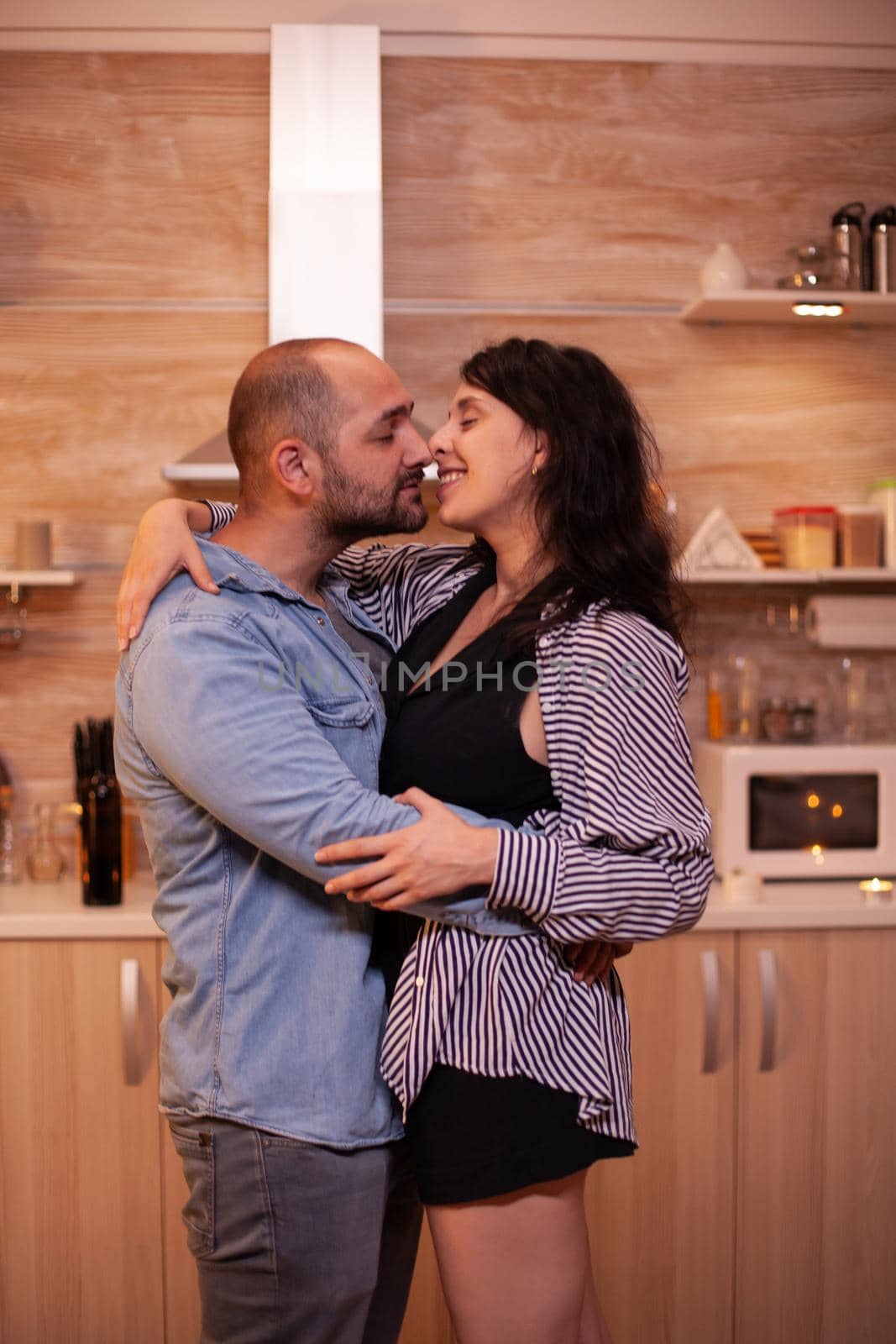 Couple feeling good while dancing in kitchen during dinner. Happy in love couple dining together at home, enjoying the meal, smiling, having fun, celebrating their anniversary.