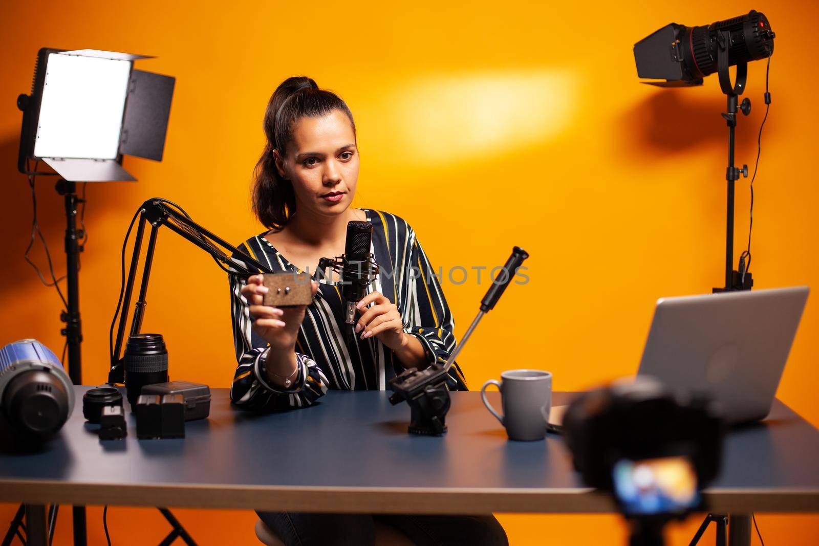 Influencer holding microphone while talking about her vlog equipment. Social media star making online internet content about video equipment for web subscribers and distribution, film