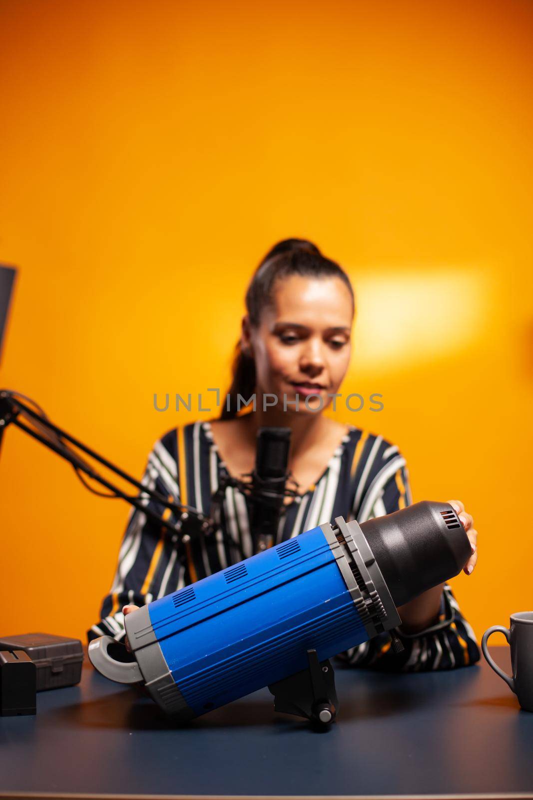 Filmmaker presenting continous light in home studio for subscribers. Social media star making online internet content about video equipment for web subscribers and distribution, film