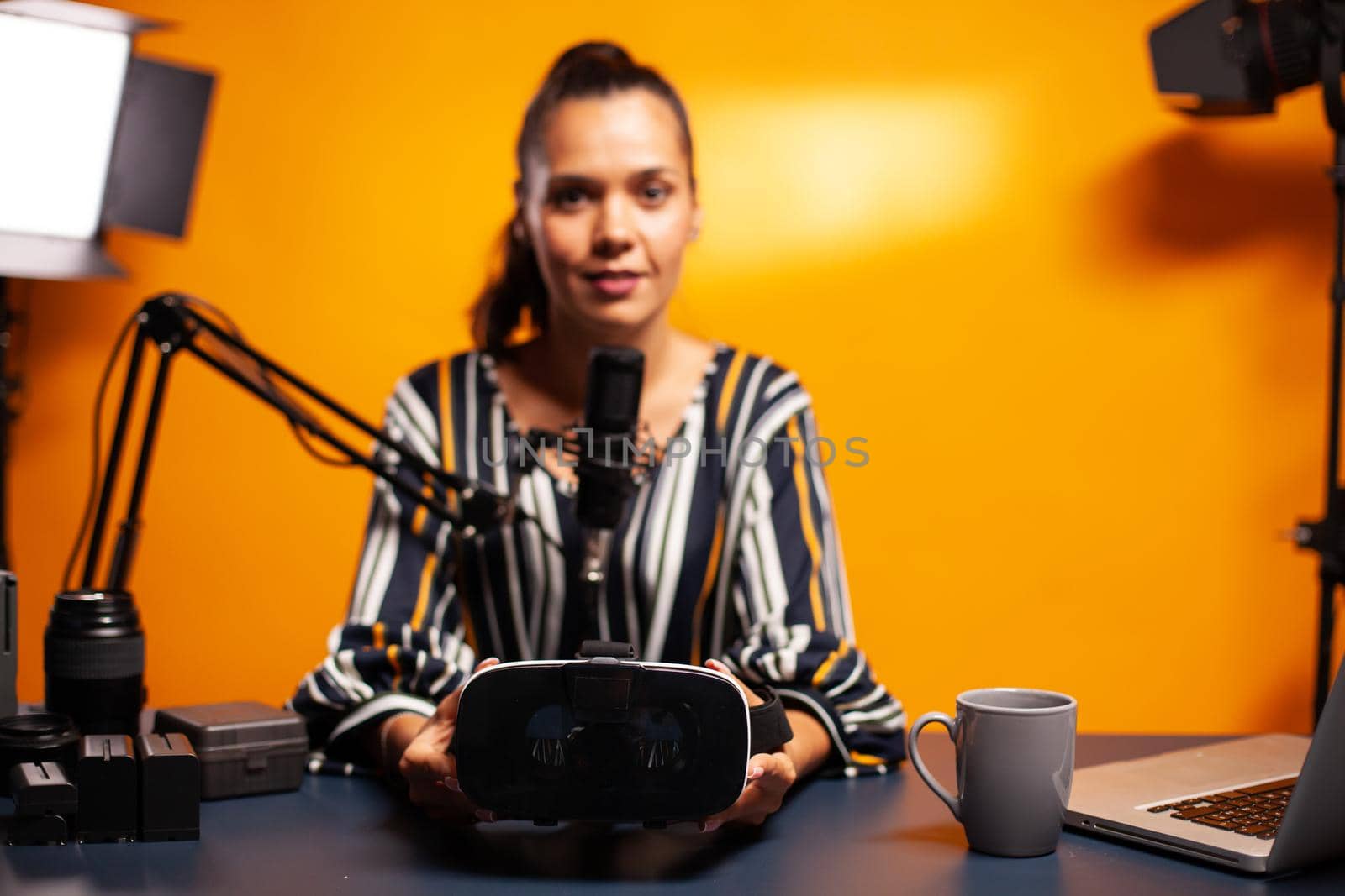 Woman holding headset while recording video blog in home studio. Video blog studio review of weareble technology with stereoscopic cyber reality, electronics gadget experience, gaming industry
