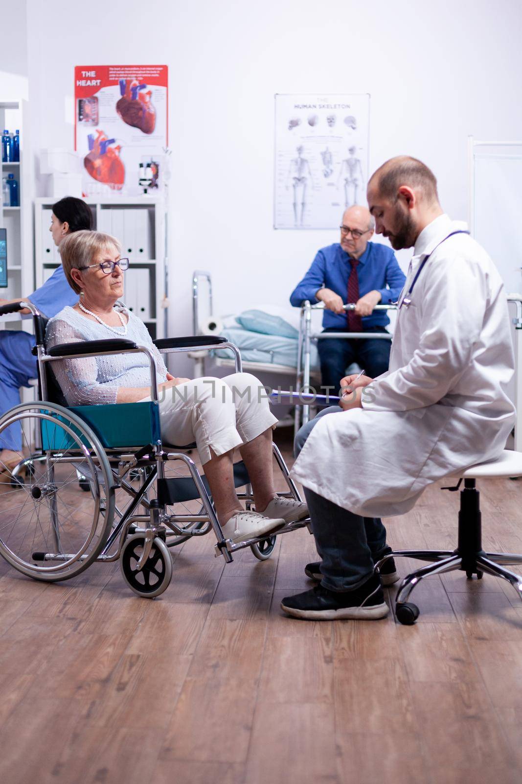 Disabled senior woman sittinf in wheelchair during medical consultation in recovery clinic. Man with disabilities ,walking frame sitting in hospital bed. Health care system, patients.