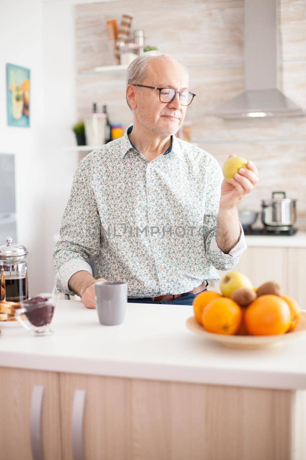 Elderly aged man looking at green apple by DCStudio