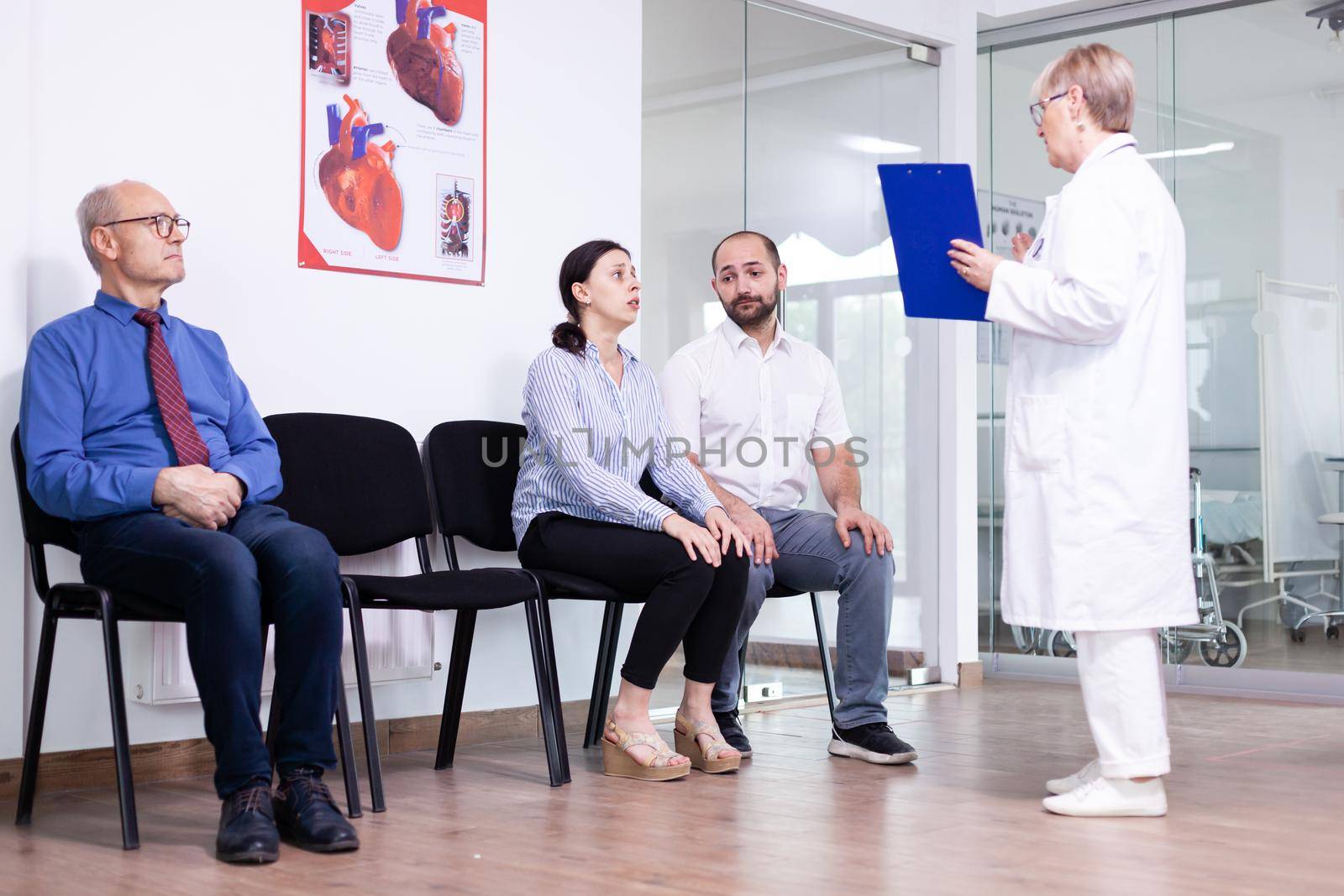 Woman crying looking at doctor after unfavorable news in hospital waiting area. Stressed man and woman during medic appointment. Man leaving clinic.