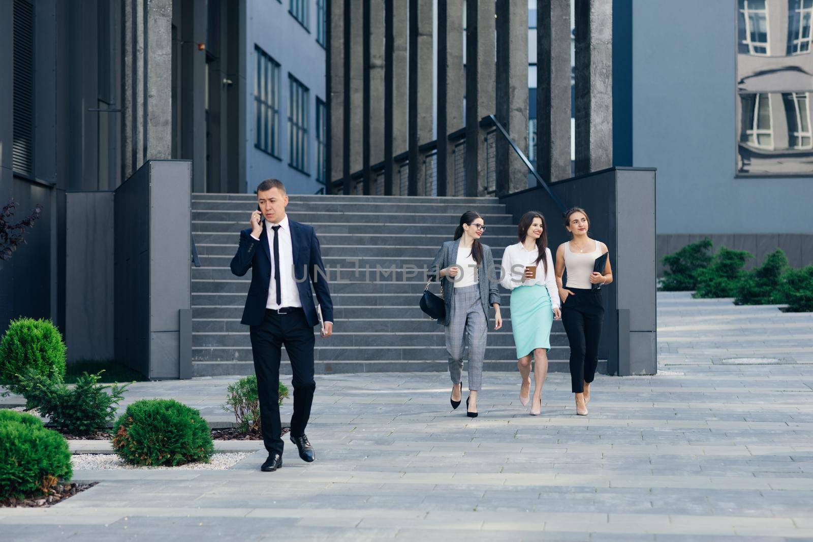 Handsome Businessman Wearing Suit Talking on the Phone Walking near Bussiness Centre. Successful Business. Wearing Classical Suit. Social Network. Apps. Smartphones by uflypro