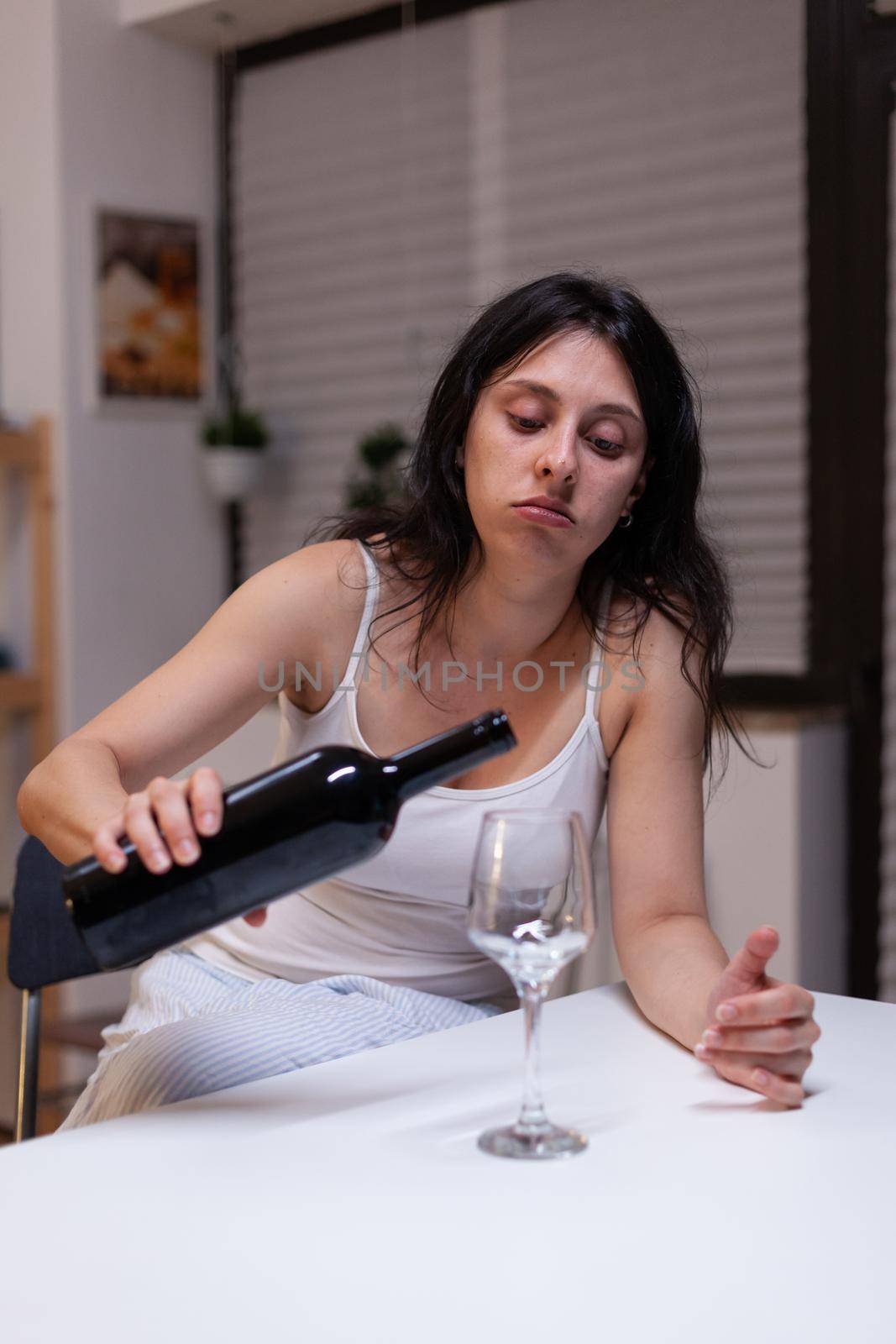 Young adult drinking wine alone in kitchen at home by DCStudio