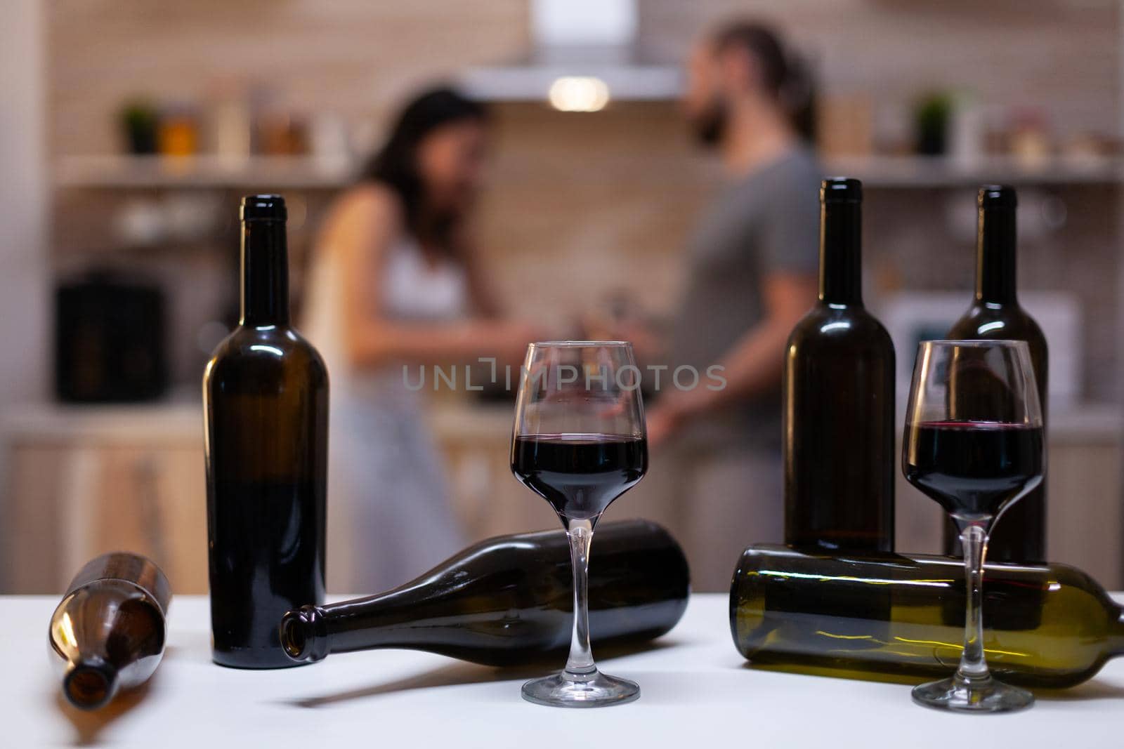 Close up of bottles and glasses filled with wine, liquor, booze and alcoholic beverage for alcohol addicts in background chatting. Intoxicated drunk people with unhealthy addiction