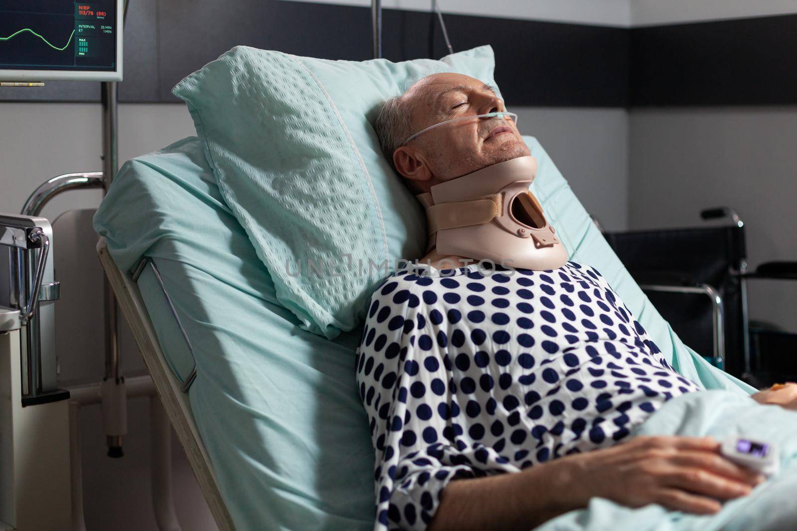 Elderly man laying in hospital room bed wearing cerival collar by DCStudio