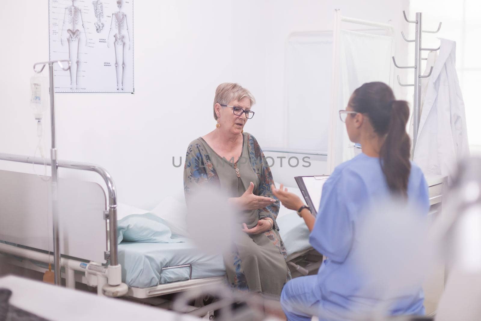 Shot of nurse examining senior patient and discussing about treatment for her illness.