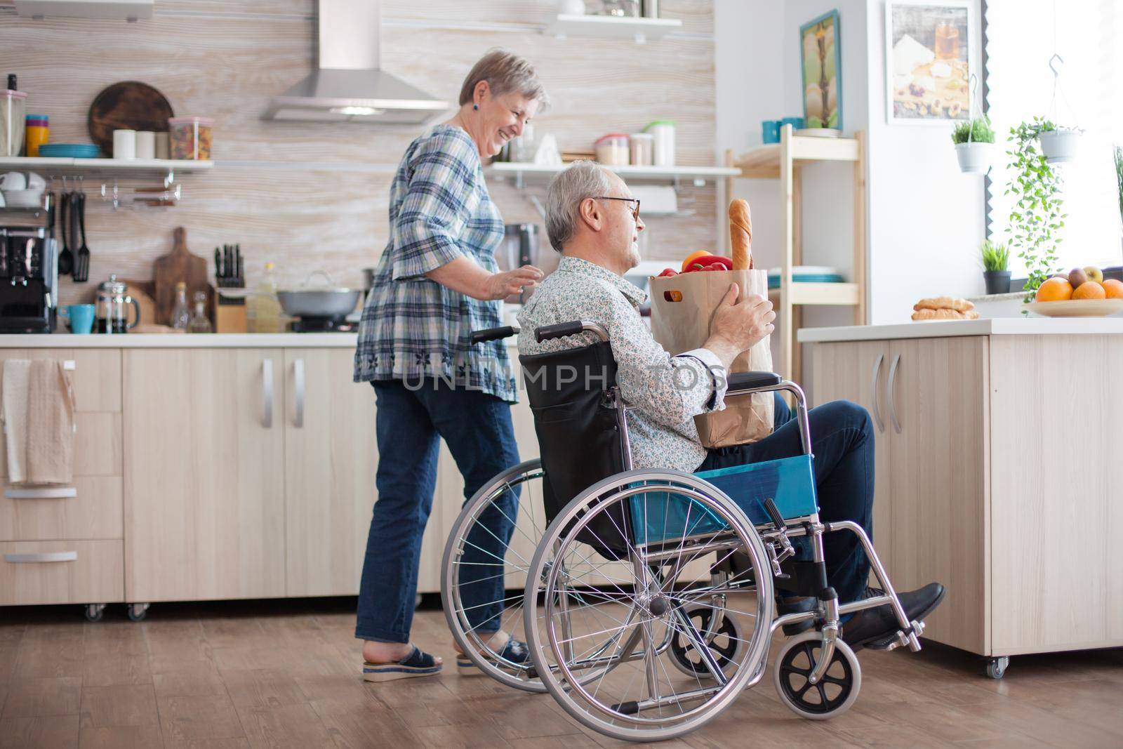 Cheerful wife helping disabled husband by DCStudio