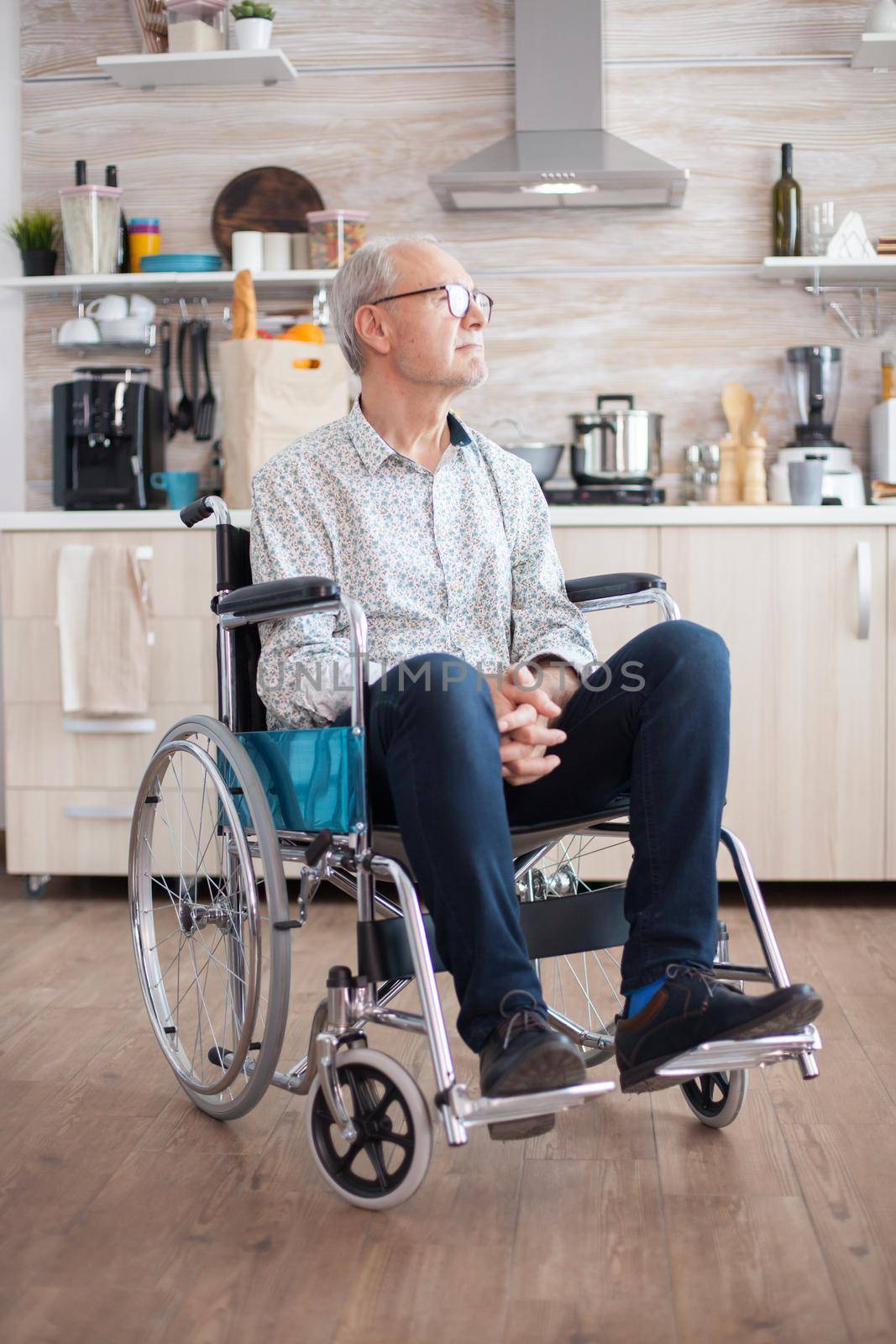 handicapped senior man in wheelchair feeling lonely looking on the window. Elderly handicapped pensioner after injury and rehab, paralysis and disability for depressed invalid full of sorrow, worry and sad face. Retirement period for old people