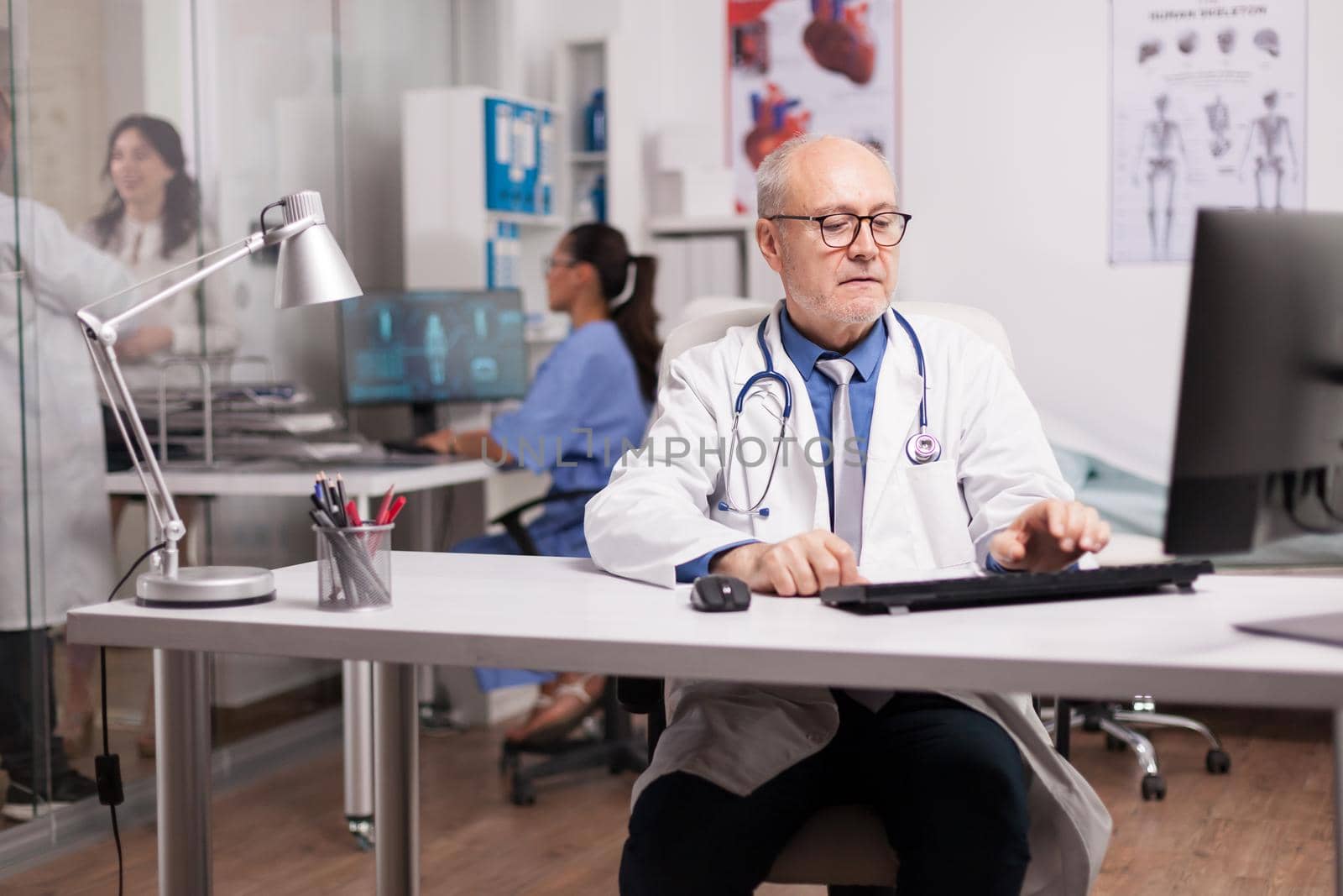 Elderly aged doctor using computer by DCStudio