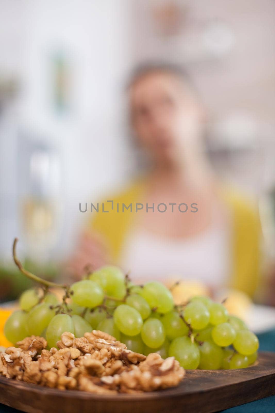 Close up of tasty grapes on wooden table with female blurred in the background.