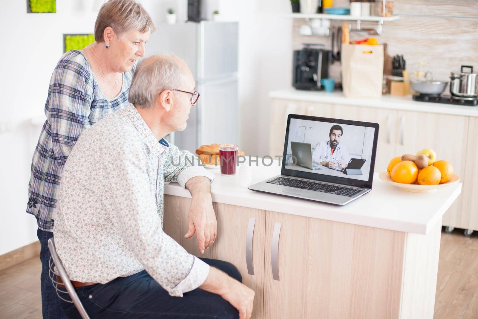 Senior patients on video conference with doctor using laptop in kitchen. Online health consultation for elderly people drugs ilness advice on symptoms, physician telemedicine webcam. Medical care internet chat