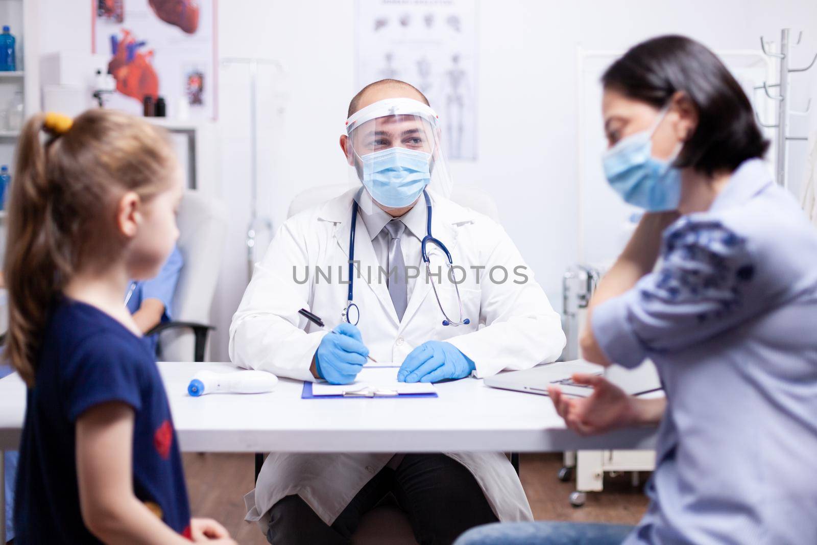 Doctor wearing face mask agaisnt coronavirus explaining diagnosis to mother of child. Health pediatrician specialist providing health care services consultations treatment.