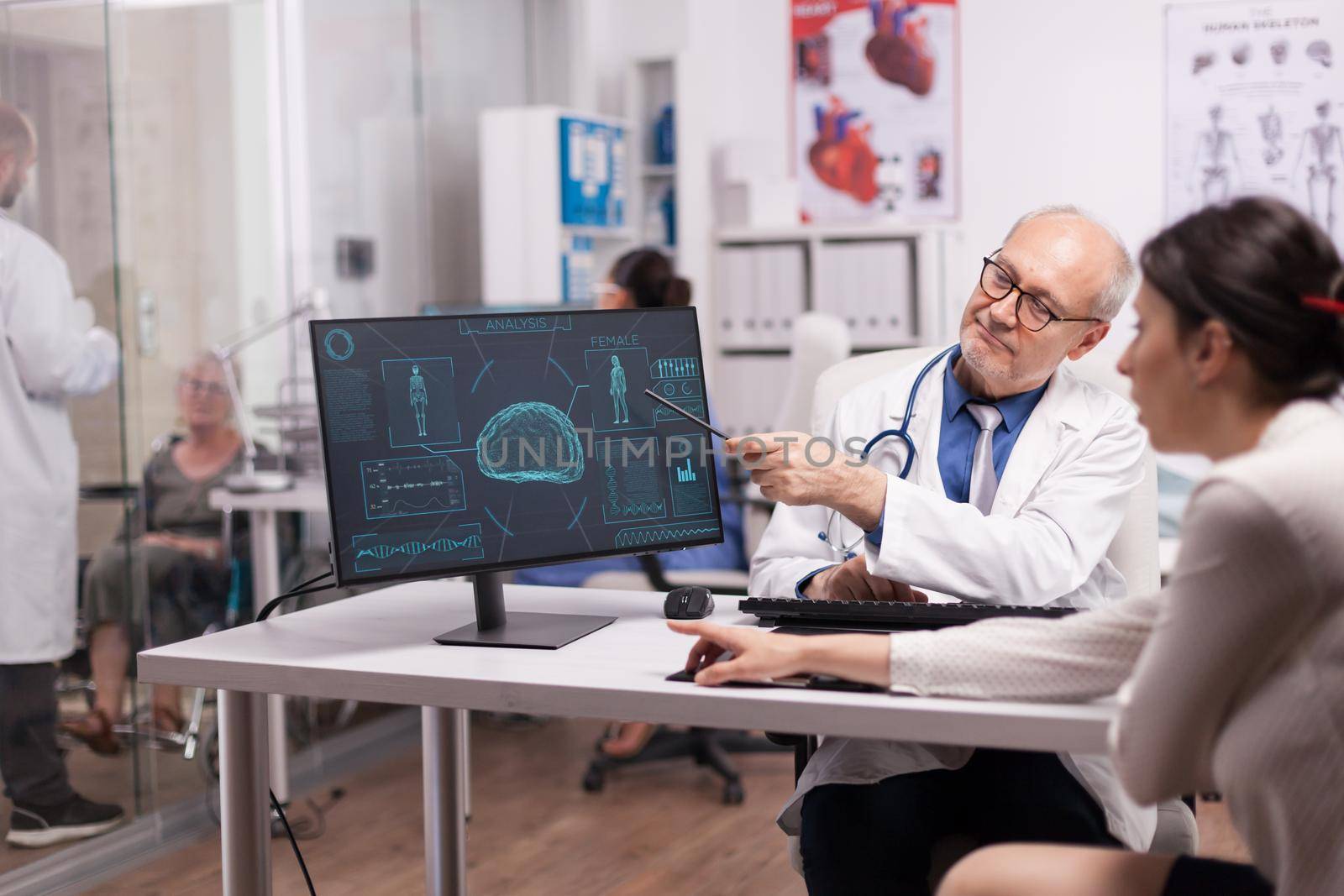 Doctor explaining x-ray for sick patient in hospital office before brain surgery. Disabled mature woman in wheelchair discussing with young radiologist.