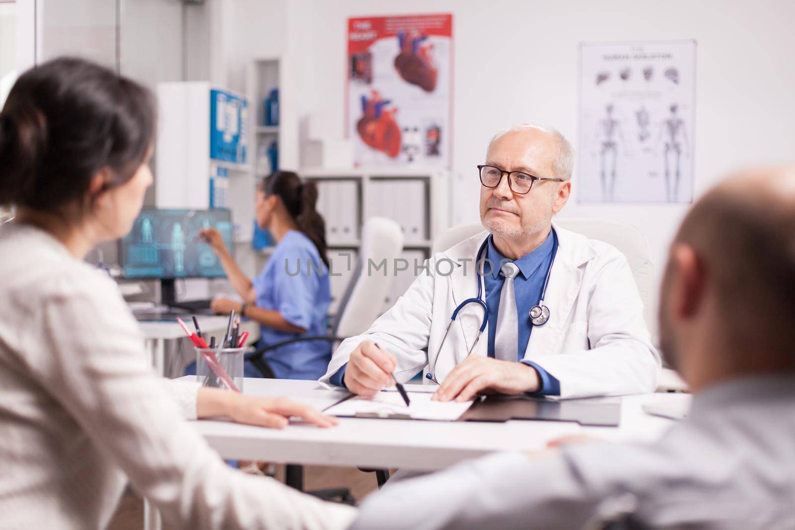 Senior doctor with grey hair during patient examination by DCStudio