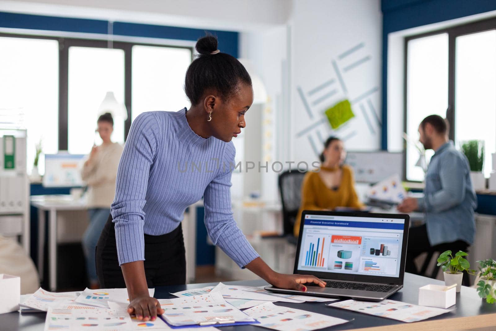 Concentrated black african businesswoman scroling through statistics by DCStudio