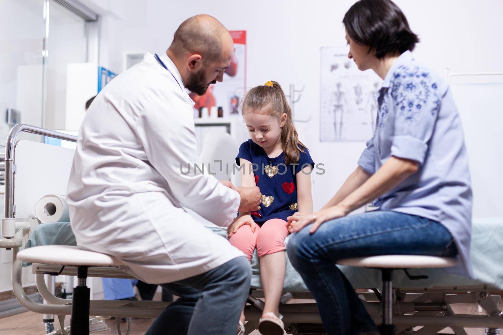 Child having arm pain during medical examination in hospital office. Healthcare physician specialist in medicine providing health care services treatment consultation.
