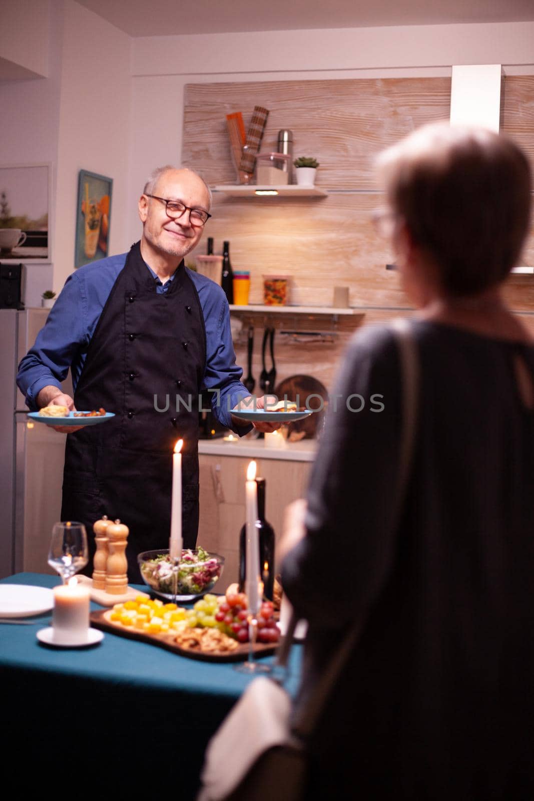 Happy senior man holding food plates by DCStudio