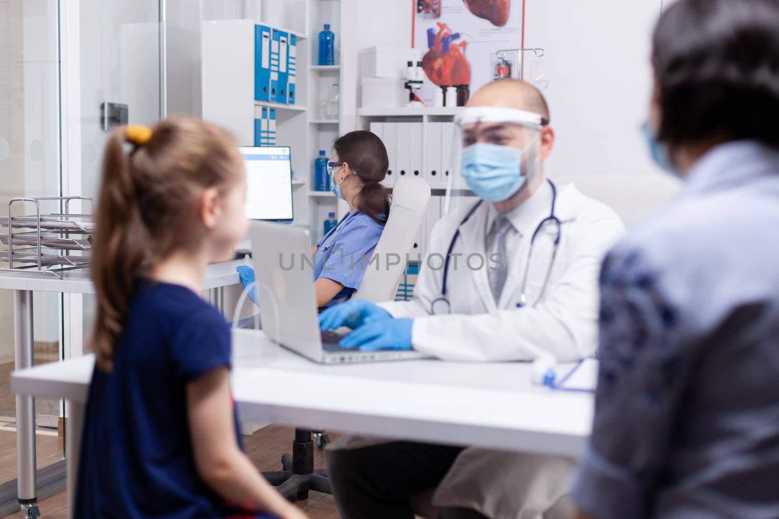 Nurse wearing face mask in hospital office working on computer. Specialist in medicine providing health care services consultation, radiographic treatment in clinic cabinet hospital