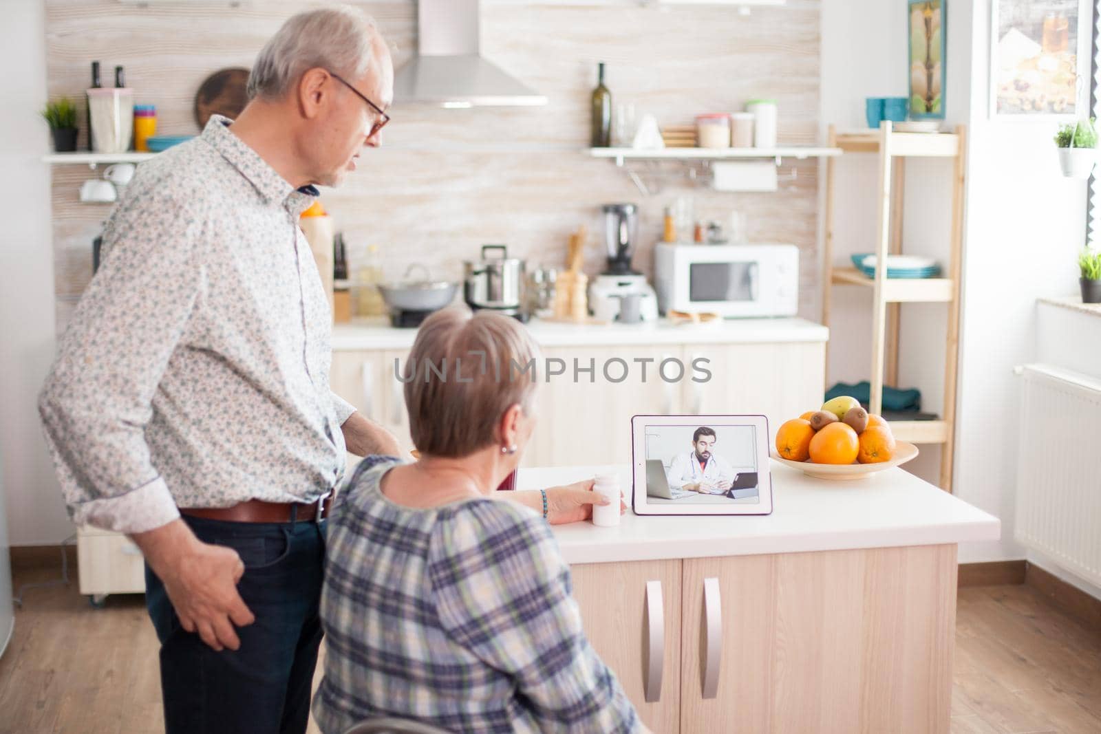 Old couple having a discussion with doctor on video call. Video conference with doctor using laptop in kitchen. Online health consultation for elderly people drugs ilness advice on symptoms, physician telemedicine webcam. Medical care internet chat