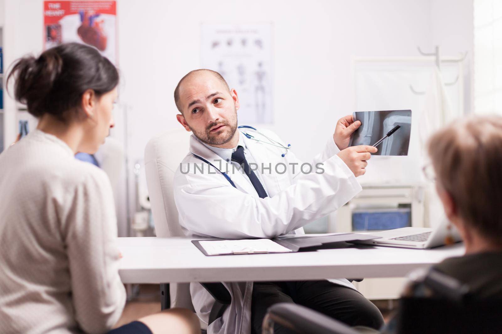 Doctor showing knee injury on x-ray image by DCStudio
