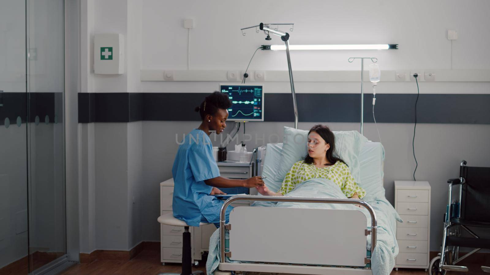 Afro-american nurse checkup sick woman analyzing pulse using medical oximeter by DCStudio